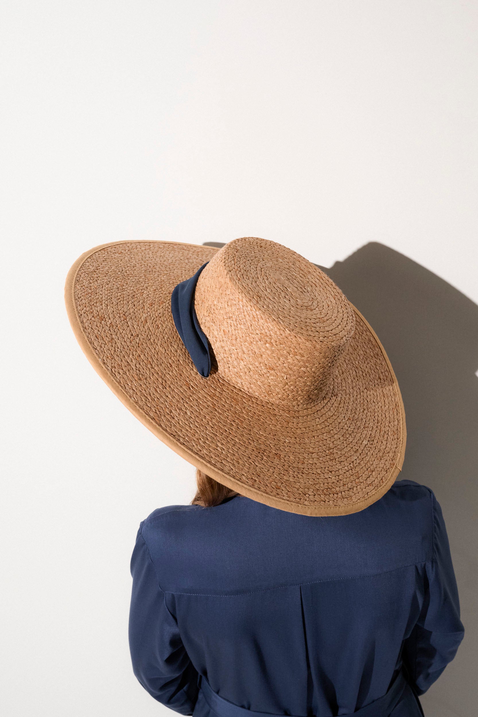 Chapeau anti-UV en paille beige avec large bord pour femme, offrant une protection solaire UPF50+ lors des journées ensoleillées.