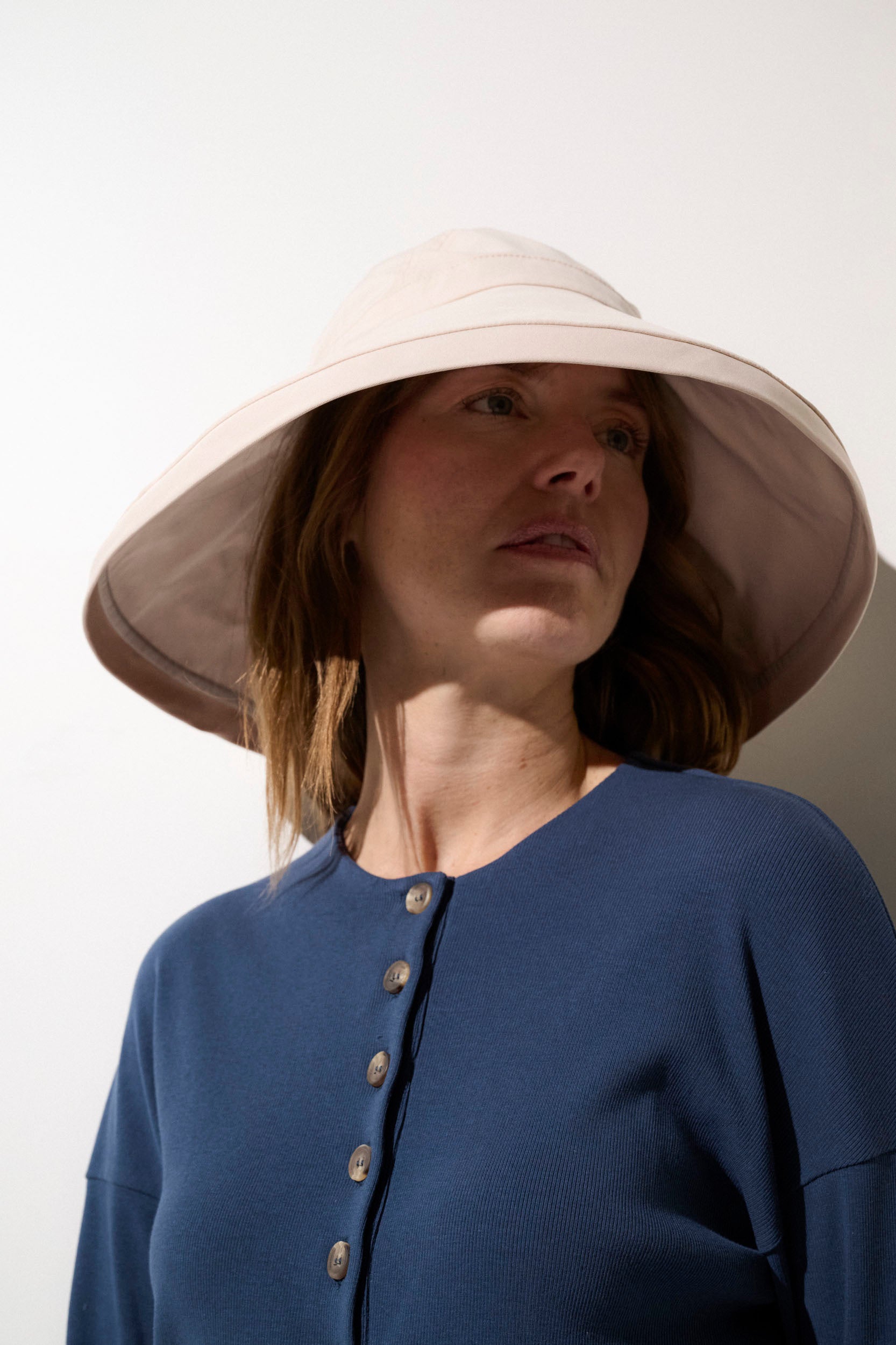 Chapeau anti-UV beige UPF50+ porté par une femme, idéal pour une protection solaire lors d'activités extérieures.