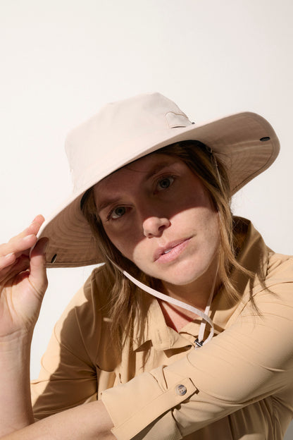 Chapeau anti-UV beige UPF50+ porté par une femme, léger et idéal pour les activités en plein air et la protection solaire.