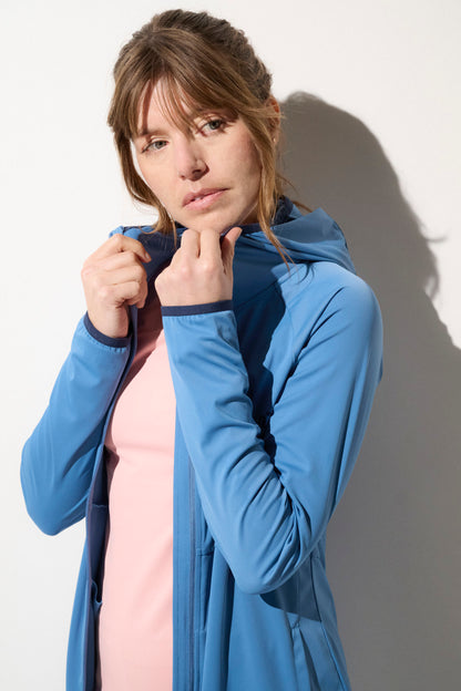 Femme portant une veste anti-UV bleu avec capuche, légère et respirante, offrant une protection solaire UPF 50+.