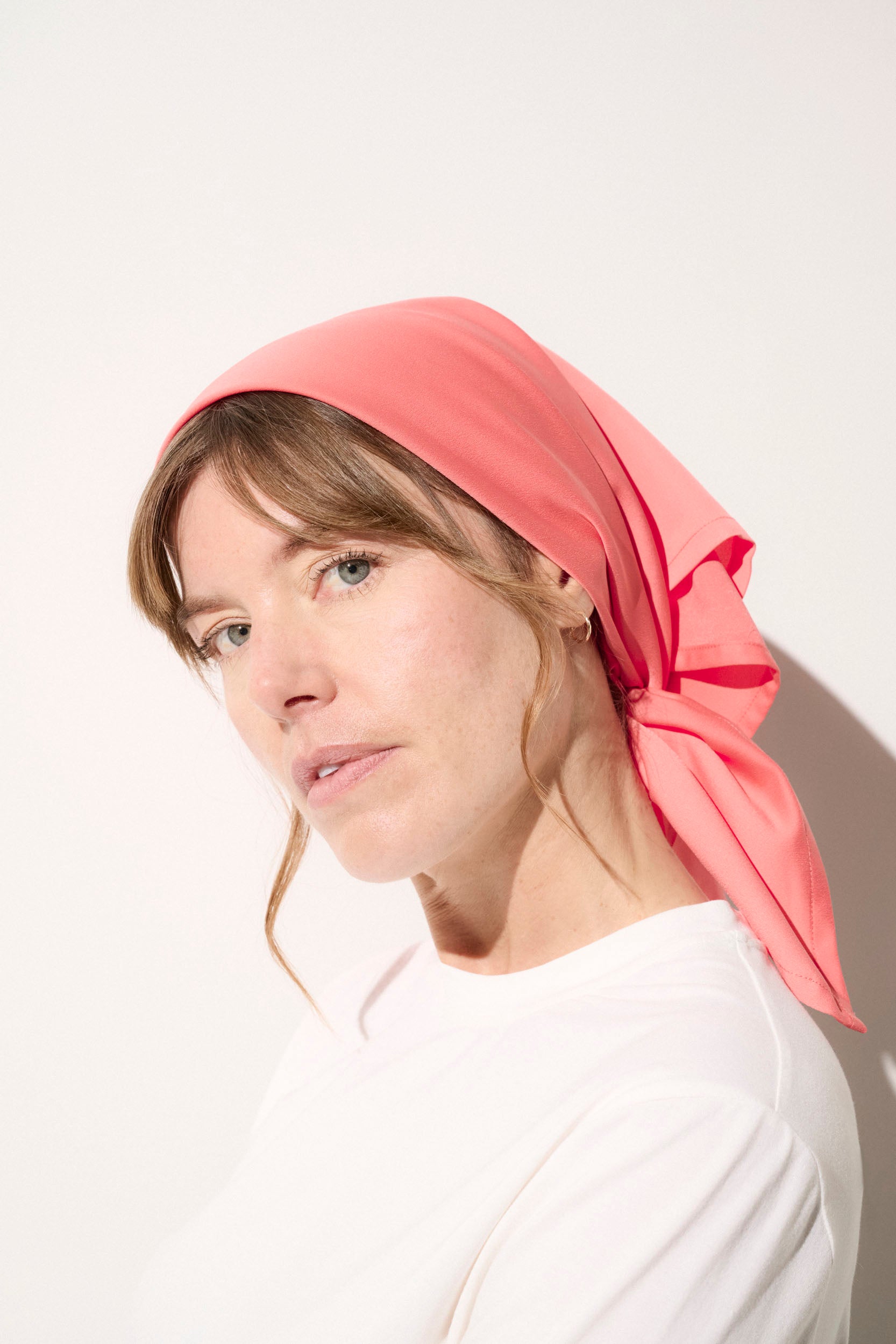 Foulard anti-UV rose pour femme, UPF 50+, porté élégamment, idéal pour la protection solaire lors des journées ensoleillées.