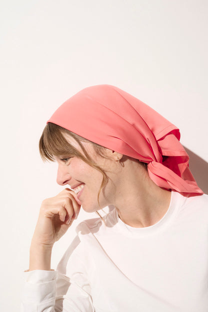 Foulard anti-UV rose pour femme, élégant et léger, offrant protection solaire UPF50+, porté à la plage ou lors de sorties ensoleillées.