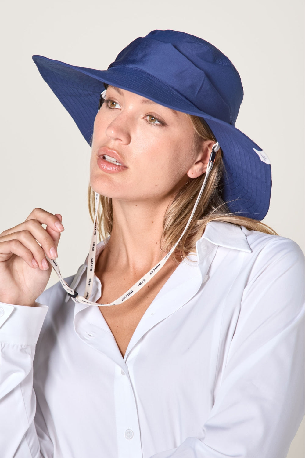 Chapeau anti-UV bleu pour femme, offrant une protection solaire avec jugulaire réglable.