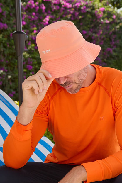 Bob anti-UV Sorbet Abricot sur un homme, idéal pour se protéger du soleil lors d'activités en extérieur.