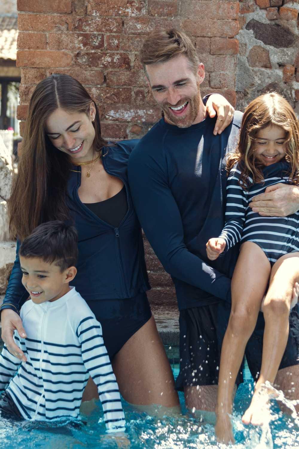 Famille en vêtements anti-UV, maillot une pièce et lycra rayé, jouant dans l'eau, protection solaire UPF50+.